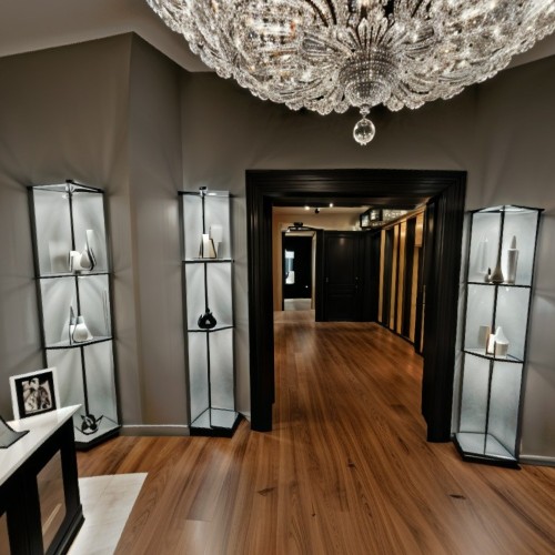 Lighting Showroom with Chandeliers and Fixtures: A spacious lighting showroom showcasing a range of chandeliers, pendant lights, and wall sconces. The room is dimly lit to emphasize the warm glow of each fixture, creating a cozy, ambient atmosphere as the lights cast reflections and shadows.